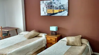 a bedroom with two beds and a picture on the wall at Pension Santa Rita in Santiago de Compostela