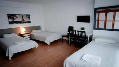 a room with two beds and a desk with a chair at Pension Santa Rita in Santiago de Compostela