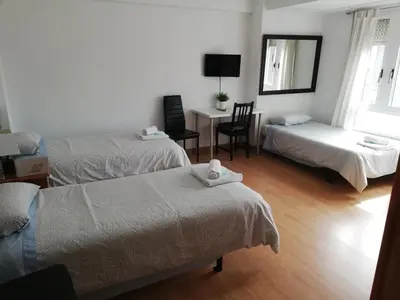 a room with two beds and a desk with a chair at Pension Santa Rita in Santiago de Compostela