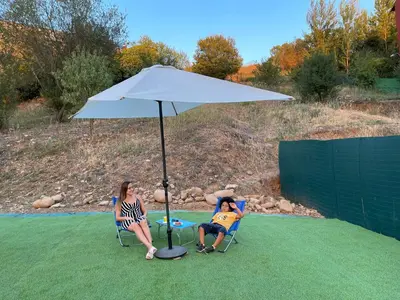 two people sitting in chairs under an umbrella at La Rosa Azul Rooms-Grupo Rosa Azul in Ponferrada
