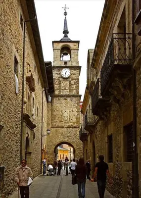 people walking down a street with a clock tower at La Encina Azul Rooms-Grupo Rosa Azul in Ponferrada