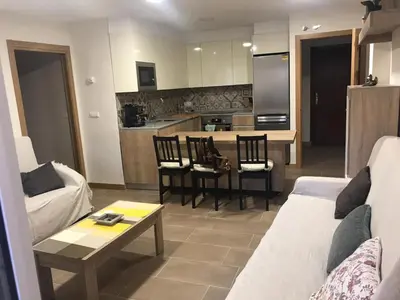a living room with a couch and a table and a kitchen at La Encina Azul Rooms-Grupo Rosa Azul in Ponferrada