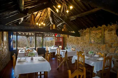 a restaurant with white tables and chairs in a room at O Palleiro do Pe do Forno in Orellán