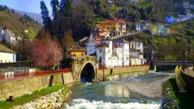 a bridge over a river with a town in the background at Apartamentos Casa Rosendo in Cangas del Narcea
