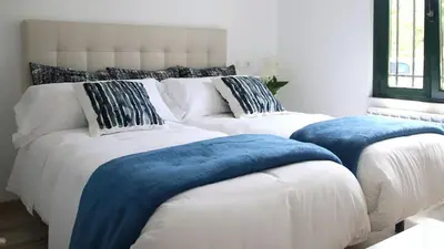 two white beds with blue pillows in a bedroom at Apartamentos AUGA in Fene