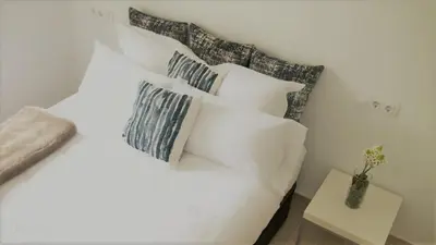 a bedroom with a white bed with pillows and a table at Apartamentos AUGA in Fene