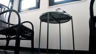 a black chair and a lamp next to a wall at Apartamentos AUGA in Fene