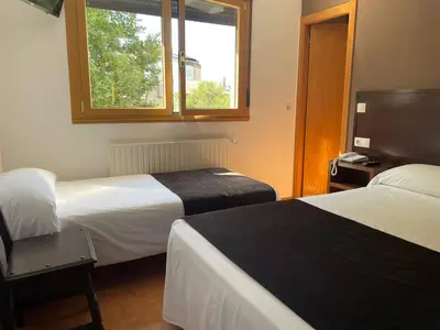 a hotel room with two beds and a window at Hotel San Lázaro in Santiago de Compostela