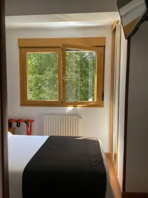 a bedroom with a bed and two windows at Hotel San Lázaro in Santiago de Compostela