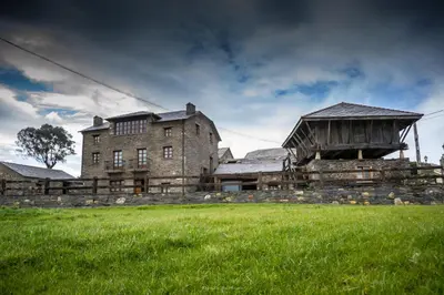 an old building with a grass field in front of it at Apartamentos Rurales El Foro in Andés