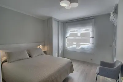 a bedroom with a bed and a chair and a window at Apartamento Playa de Altar in Barreiros