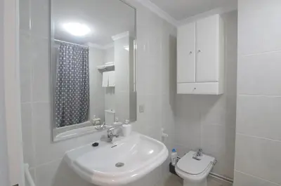 a white bathroom with a sink and a toilet at Apartamento Playa de Altar in Barreiros
