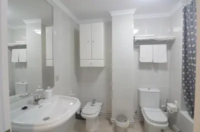 a white bathroom with a sink and a toilet at Apartamento Playa de Altar in Barreiros