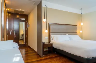 a hotel room with two beds and a hallway at Hotel Compostela in Santiago de Compostela