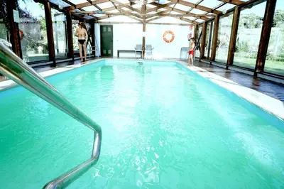 a swimming pool with blue water in a building at Hotel Rural La Peregrina in Carucedo