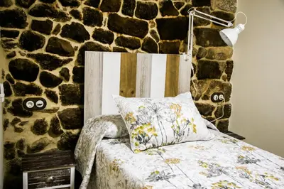 a bedroom with a bed and a stone wall at A casa da Igrexa in Ribadavia
