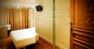 a hotel room with a bed and a glass wall at Deniké Grupo Atalaia in Santiago de Compostela