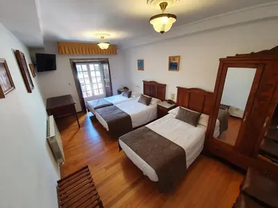 a hotel room with two beds and a mirror at Hostal Giadás in Santiago de Compostela