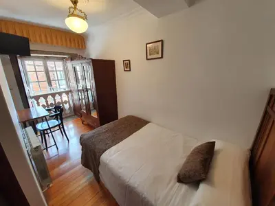 a bedroom with a bed and a dining room with a table at Hostal Giadás in Santiago de Compostela