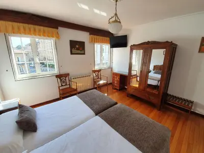a large bedroom with two beds and a mirror at Hostal Giadás in Santiago de Compostela