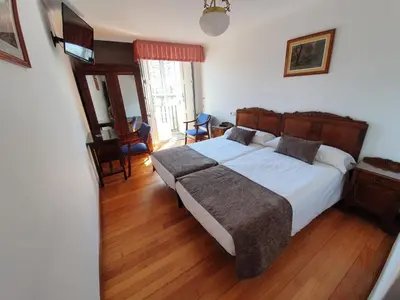 a bedroom with a large bed and wooden floors at Hostal Giadás in Santiago de Compostela