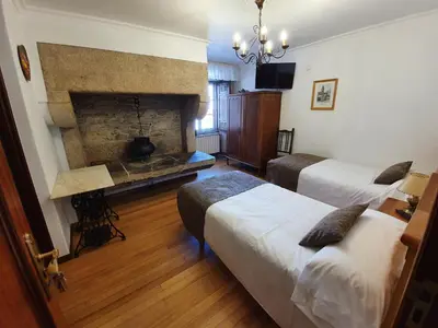a hotel room with two beds and a fireplace at Hostal Giadás in Santiago de Compostela