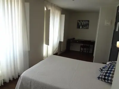 a bedroom with a white bed and a desk at Hotel Irixo in Ourense