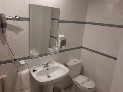 a bathroom with a sink and a toilet and a mirror at El Refugio Hostería in Rabanal del Camino