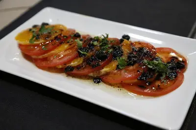 a plate of food with tomatoes on a table at El Refugio Hostería in Rabanal del Camino