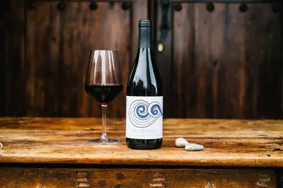 a bottle of wine and a glass on a table at El Refugio Hostería in Rabanal del Camino