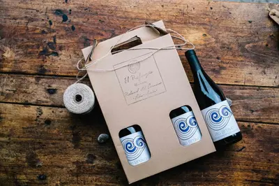 a bottle of wine and a box on a wooden table at El Refugio Hostería in Rabanal del Camino