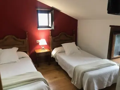 two beds in a room with red walls at Casa Navarro in O Cebreiro