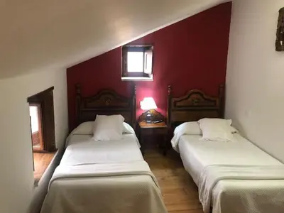 two beds in a room with red walls at Casa Navarro in O Cebreiro