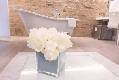 a vase with white flowers in front of a sink at Hotel Montes in Santiago de Compostela