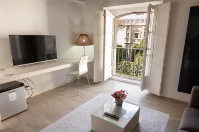 a living room with a table and a tv and a window at Hotel Montes in Santiago de Compostela
