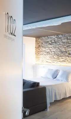 a bedroom with a bed and a stone wall at Hotel Montes in Santiago de Compostela