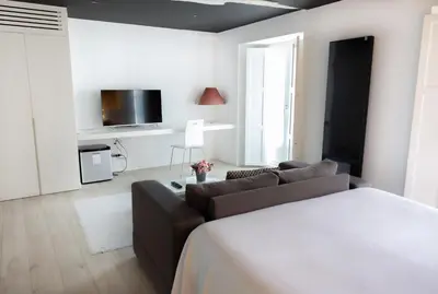 a white living room with a couch and a tv at Hotel Montes in Santiago de Compostela