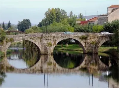 a stone bridge over a body of water at Acogedor Apartamento Ribeira Sacra in Monforte de Lemos