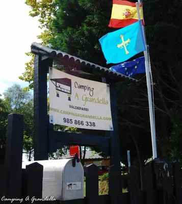 a sign with a flag and a sign for a bus at CAMPING A GRANDELLA in El Franco