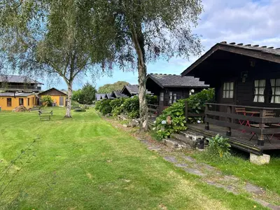 a log cabin with a yard and a house at CAMPING A GRANDELLA in El Franco
