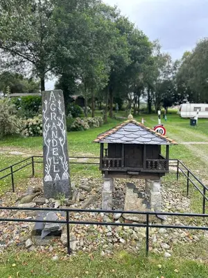 a small building with writing on it next to a fence at CAMPING A GRANDELLA in El Franco