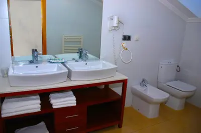 a bathroom with two sinks and a toilet at Hotel Villa de Cacabelos in Cacabelos
