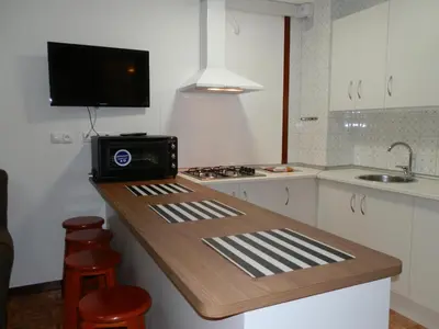 a kitchen with a counter with a stove and a sink at Apartamentos Turisticos Beatriz in Perillo