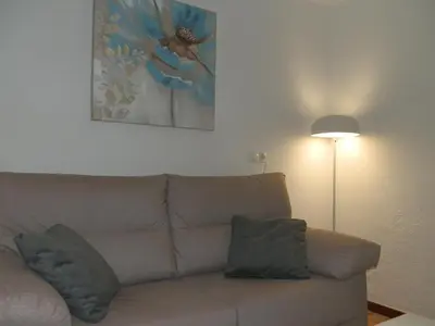 a living room with a couch and a lamp at Apartamentos Turisticos Beatriz in Perillo