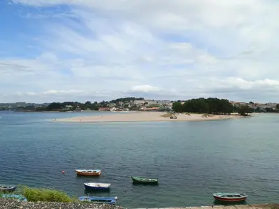 a group of boats in the water near a beach at Apartamentos Turisticos Beatriz in Perillo
