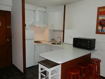 a kitchen with white cabinets and a counter with a microwave at Apartamentos Turisticos Beatriz in Perillo