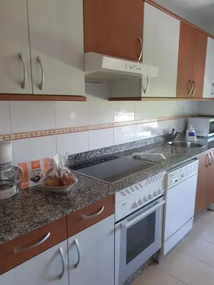 a kitchen with white appliances and wooden cabinets at El Silencio de Galadhrim in Ponferrada