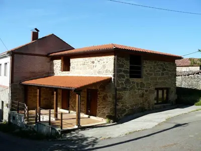 a brick house with a porch on the side of it at Apartamentos Rurales A Torre in Porqueira