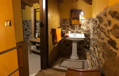 a bathroom with a sink and a stone wall at Apartamentos Rurales A Torre in Porqueira