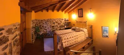a bedroom with a bed in a stone wall at Apartamentos Rurales A Torre in Porqueira
